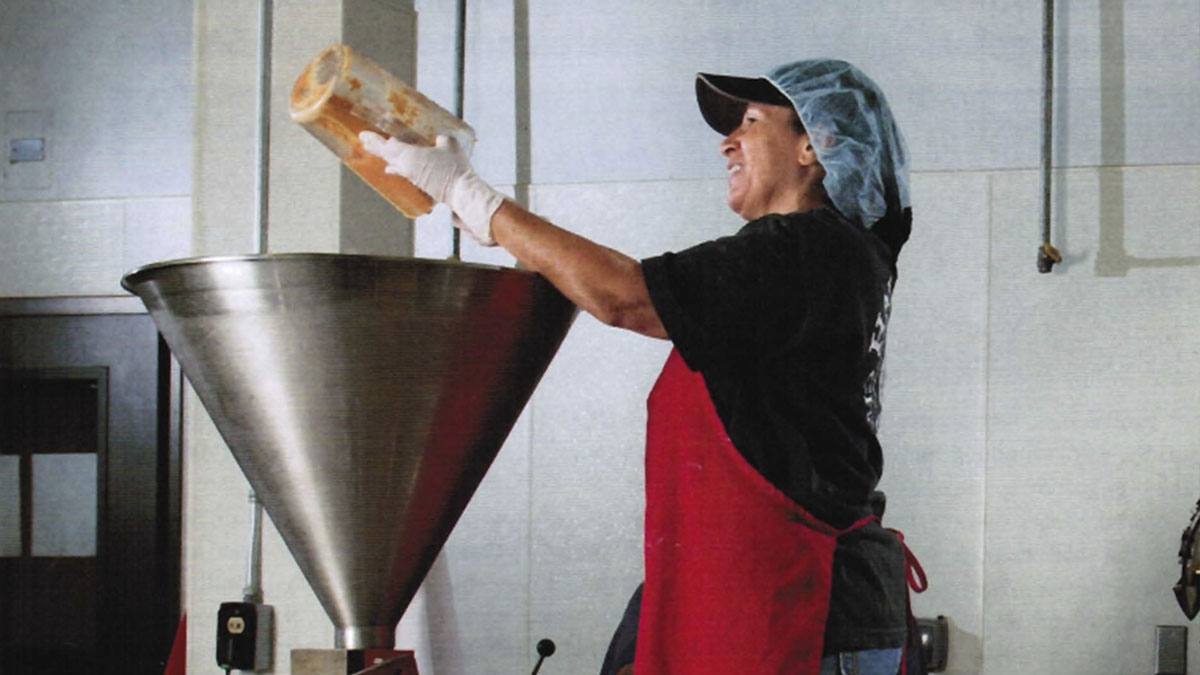 Woman putting hummus into filler machine hopper