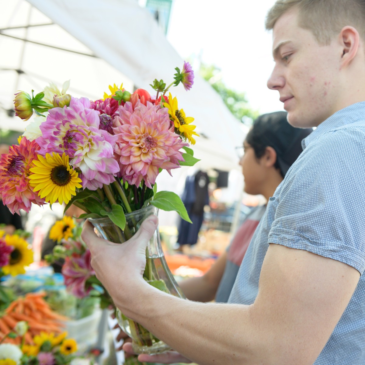 A man holds brightly colored flowers.