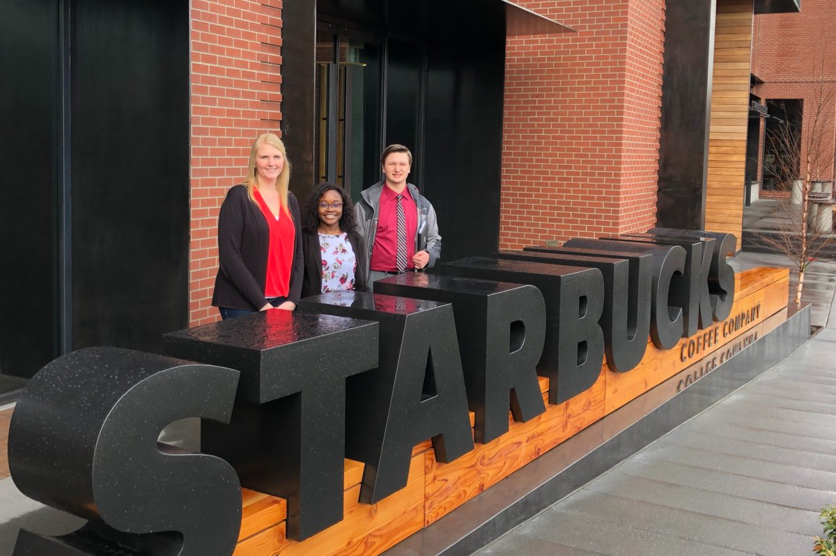 Oluwadamilola Olape and Ryan Zimmerman pose with Starbucks executive Emily Marks in front of the Starbucks building in Seattle.