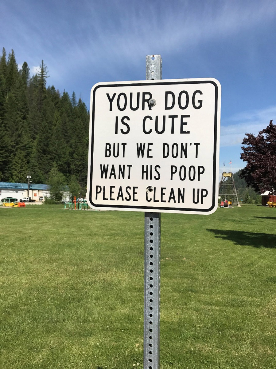 A sign in a public park reads: Your dog is cute but we don't want his poop. Please clean up.