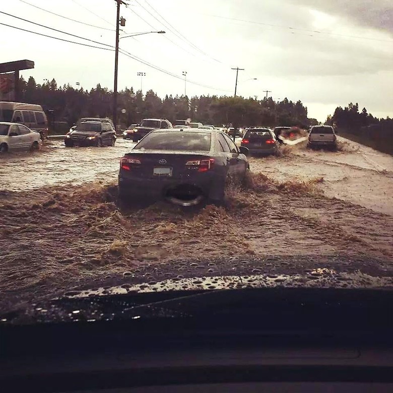 A car travels on a roadway flooded with water.