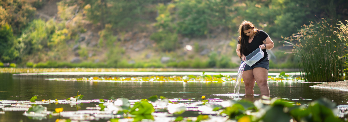 Emma Arman studies water from a bucket while standing among the lily pads of Ferman Lake. 