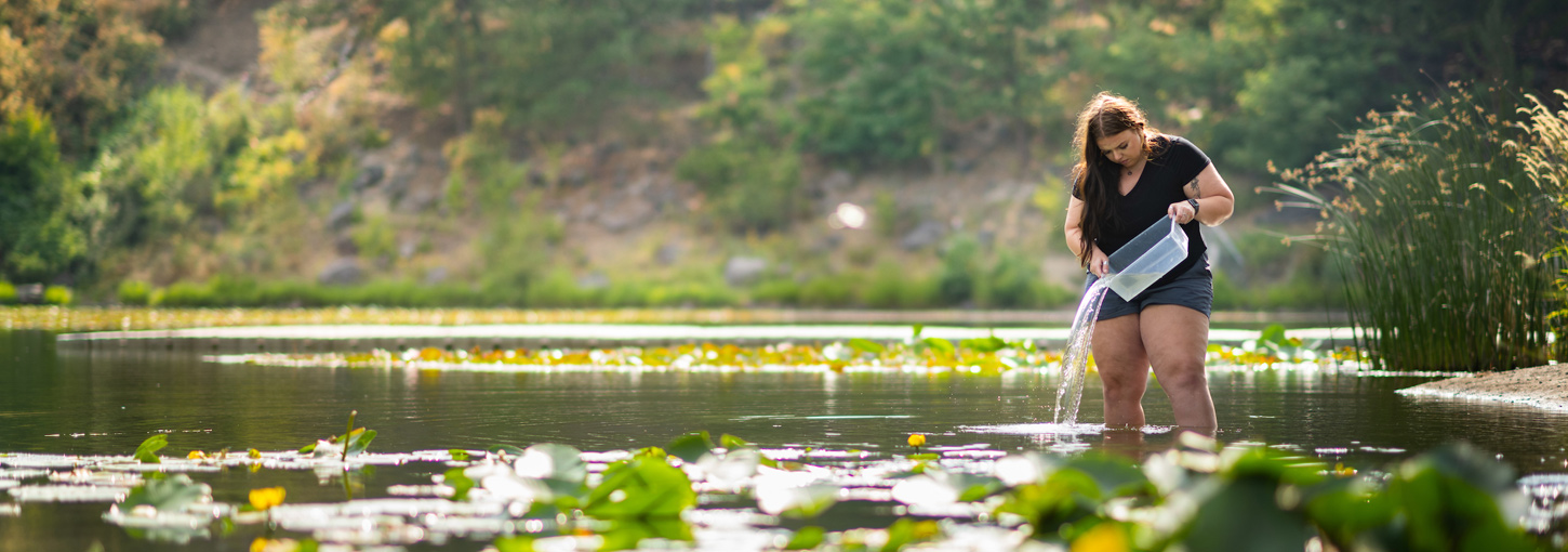 Emma Arman studies water from a bucket while standing among the lily pads of Ferman Lake.