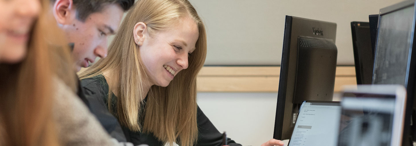 A student with her peers working at a computer.