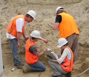 A piece of charcoal is being mapped in place on the east side of the trench. Lee Sappington, Dakota Wallen, Laura Longstaff and Kyle Parker.