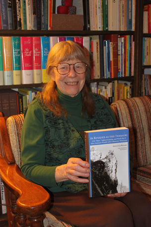 Priscilla Wegars holding her book "As Rugged as the Terrain"