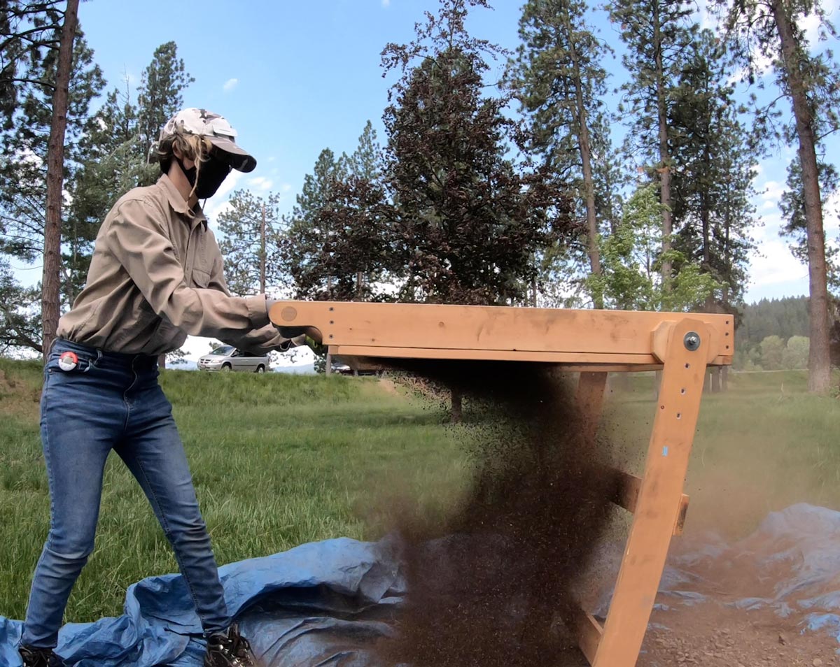 Savannah Johnson uses a screen to sieve dirt.