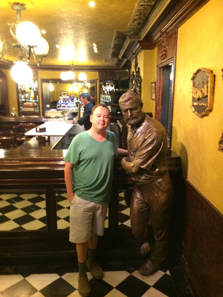Brandon Schrand in Pamplona standing next to a statue of Ernest Hemingway