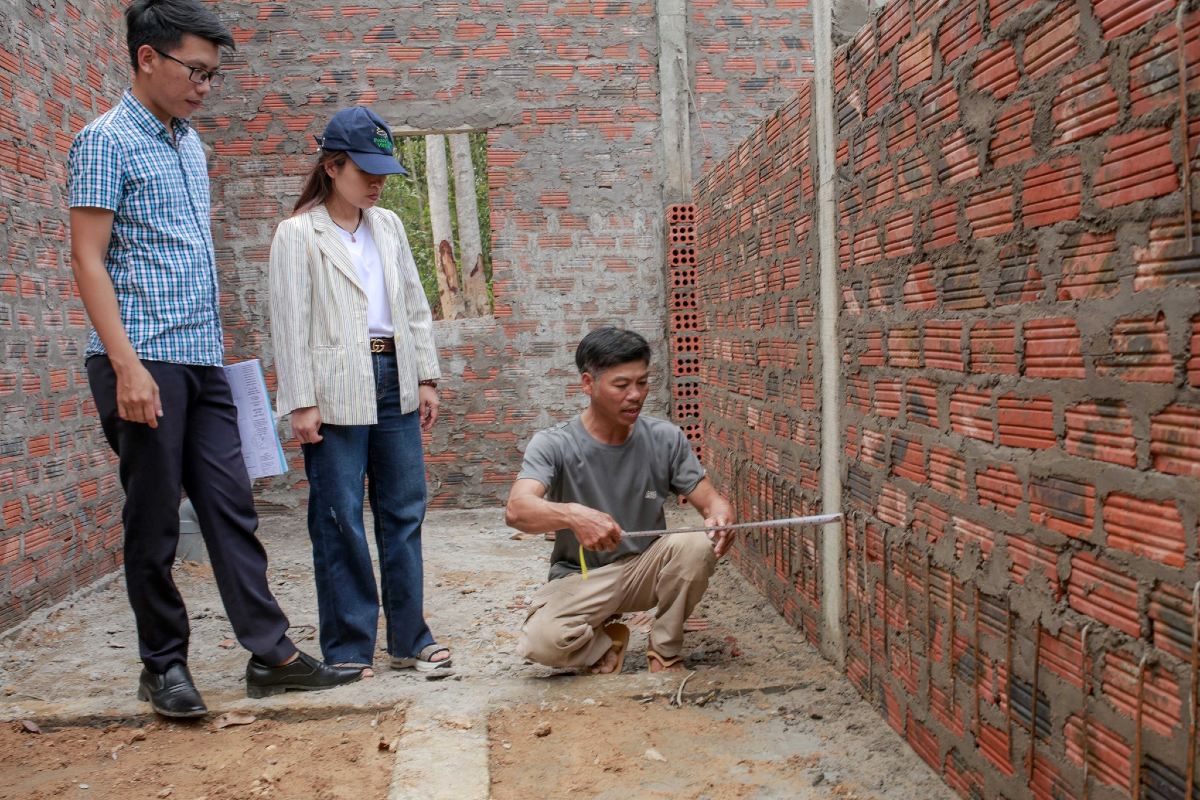 Three Vietnamese workers building a brick wall