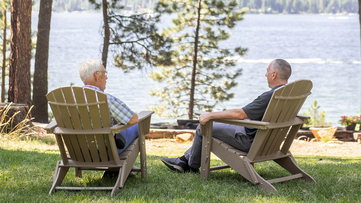  Two people sitting on lounge chairs by a body of water