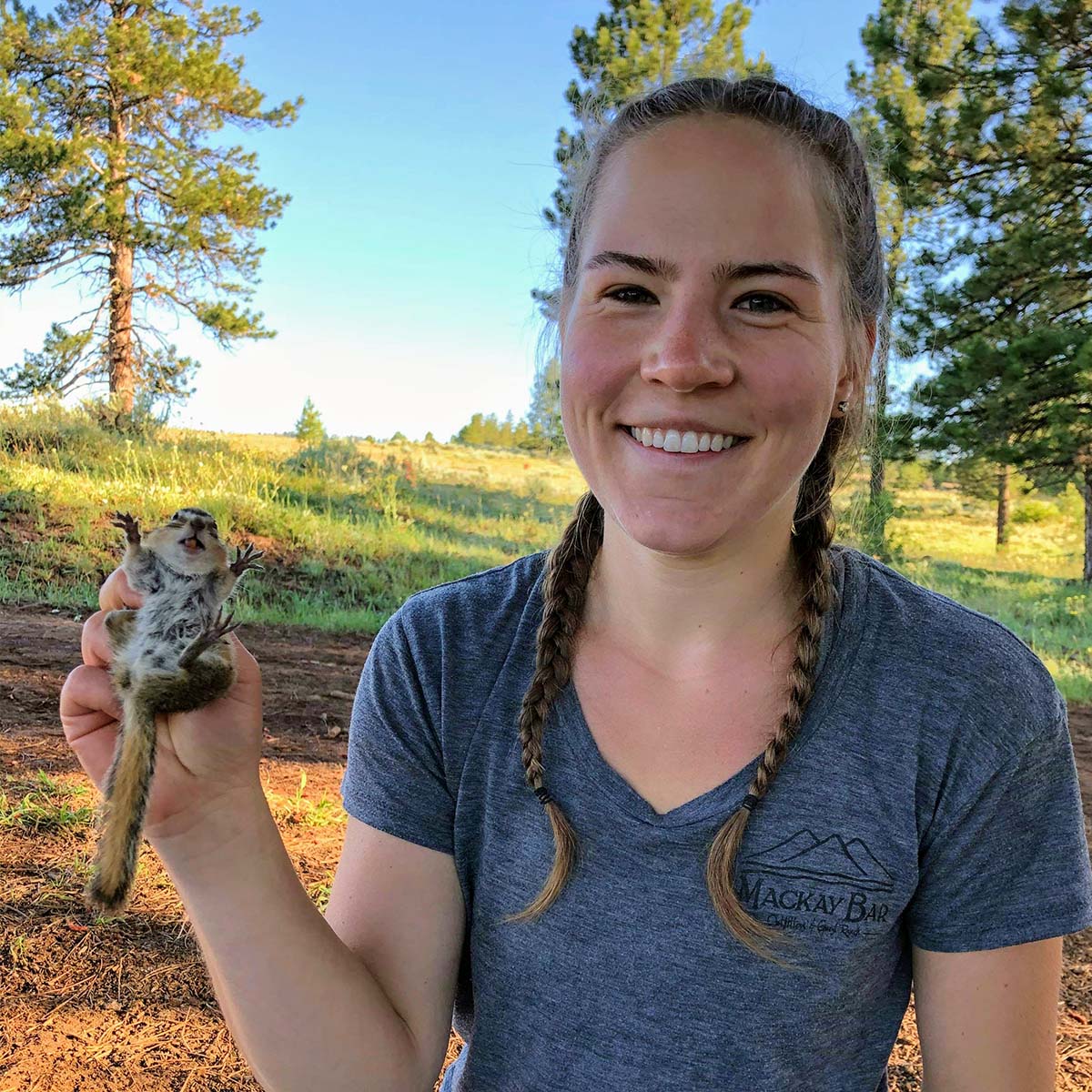Smiling researcher gently holds ground squirrel.