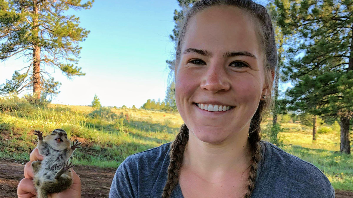 Smiling researcher gently holds ground squirrel.