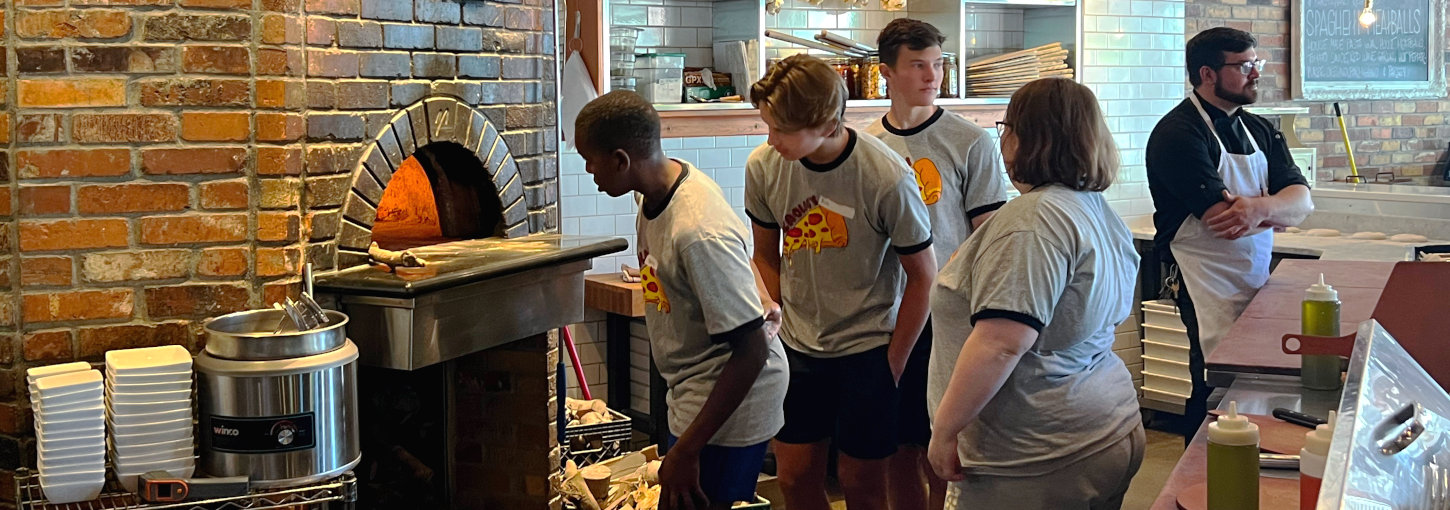 Students in front of pizza oven.