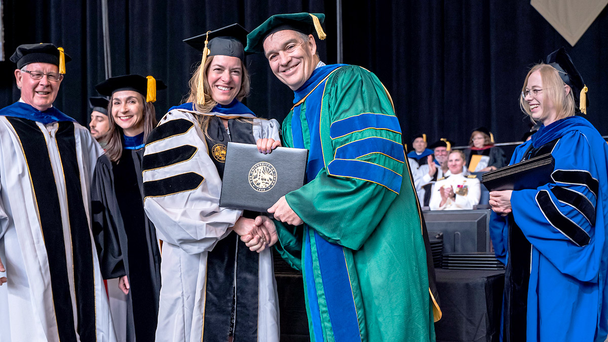 graduate student receiving diploma on stage