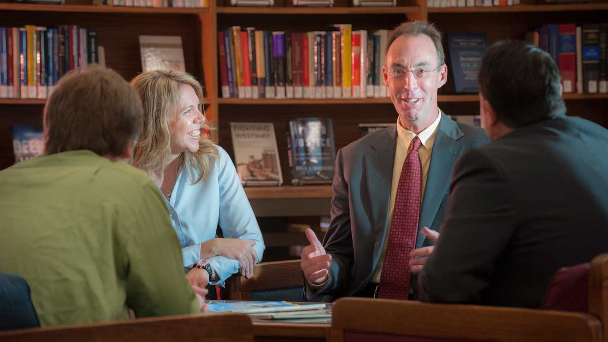 Dean Adams talking with students in the library.