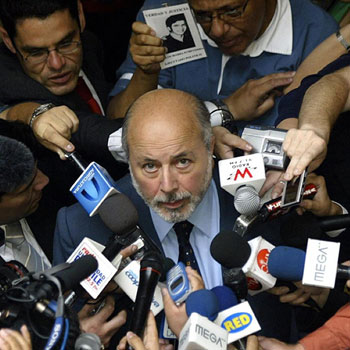 Former Judge and Justice Juan Guzmán surrounded by microphones and media members.