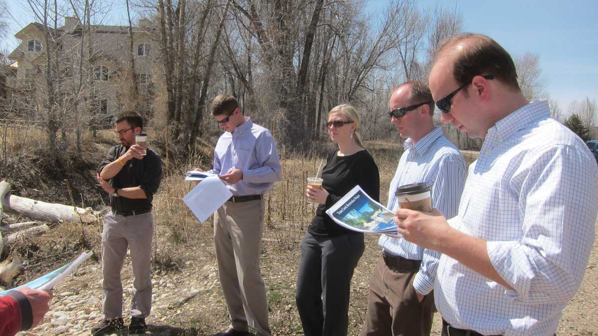 Five people outside with two people looking at documents
