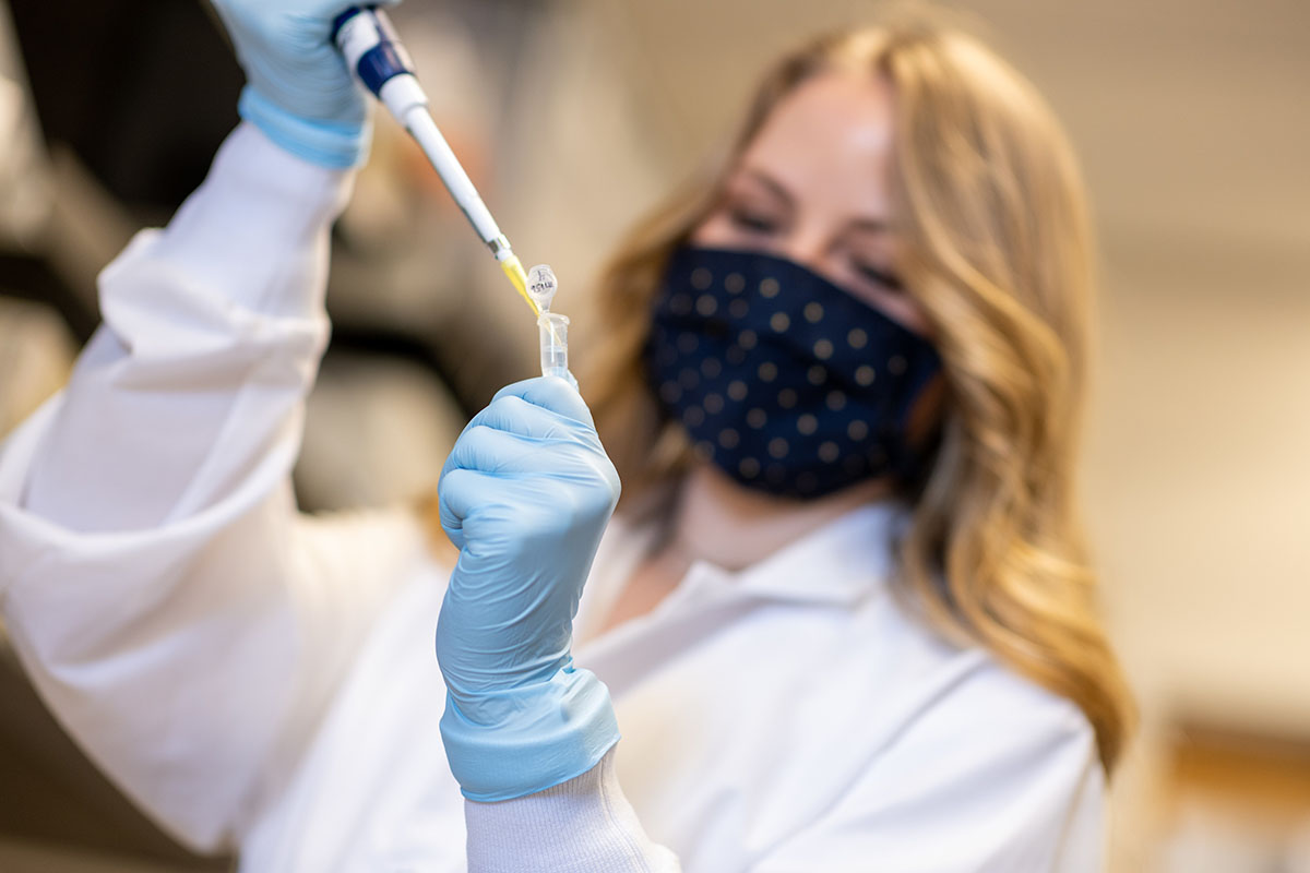 Delaney Wagers fills a vile from a syringe-like device
