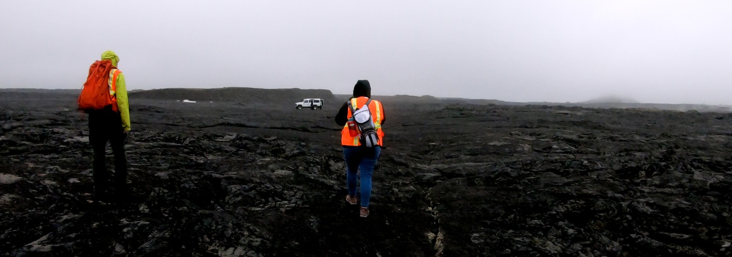 Researcher walks across black Icelandic lava flow.