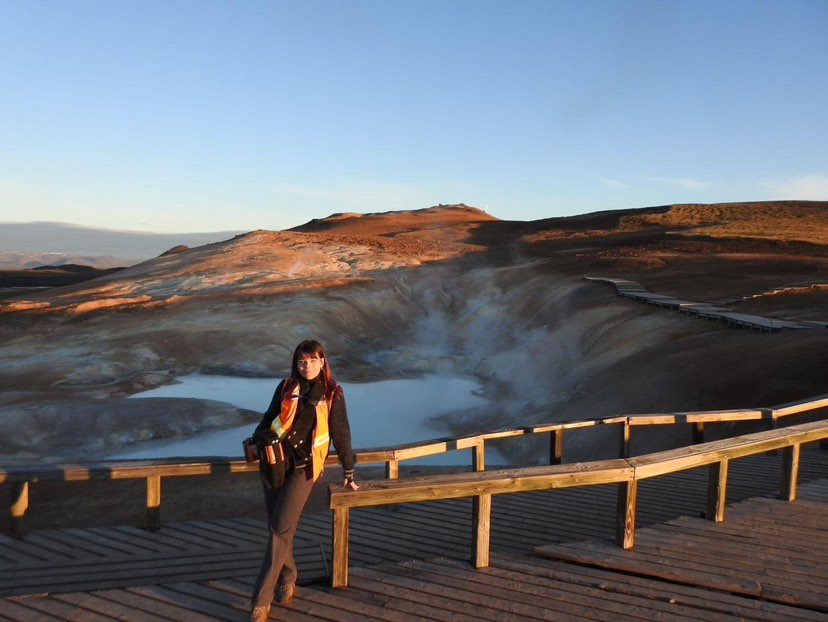 Anna Sage Ross-Browning standing by a crater filled with water.