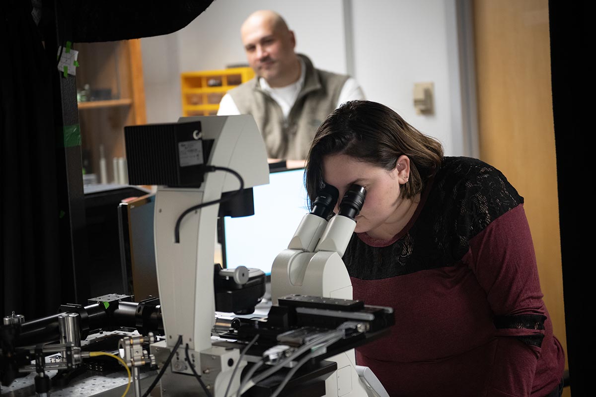 Professor Andrew Vasdekis looks on as a student uses the fluorescent microscope developed in the Vasdekis lab.