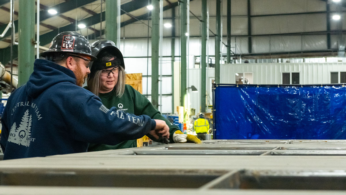 Two people wearing protective hard hats in an industrial wear house. 