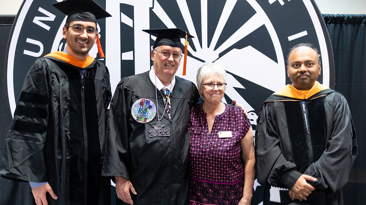 Thomas Griggs, 71, receives his University of Idaho bachelor’s degree at a May 2022 ceremony surrounded by three faculty and staff members.