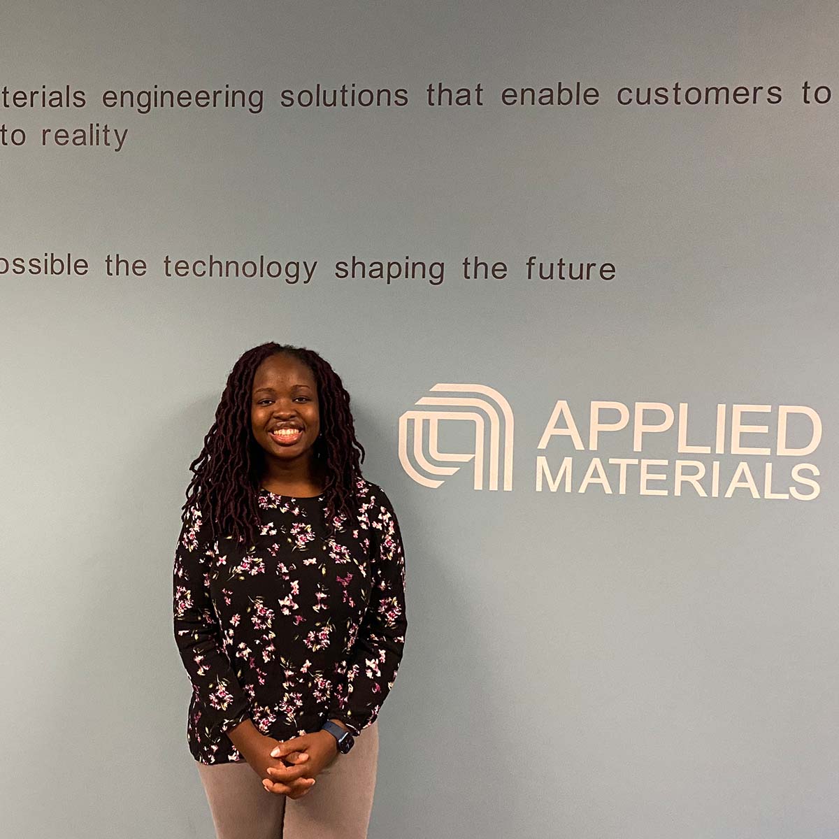 Shalom poses for a photograph in front of the Applied Materials backdrop.