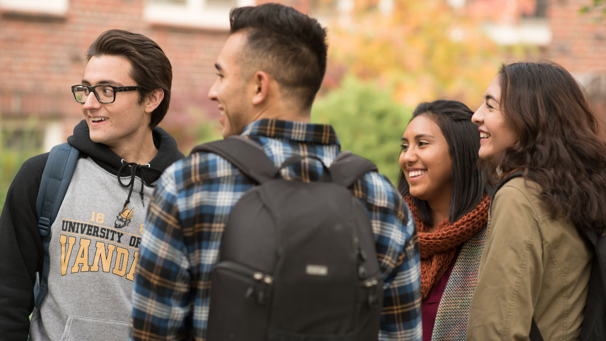 Four students laughing outside on campus