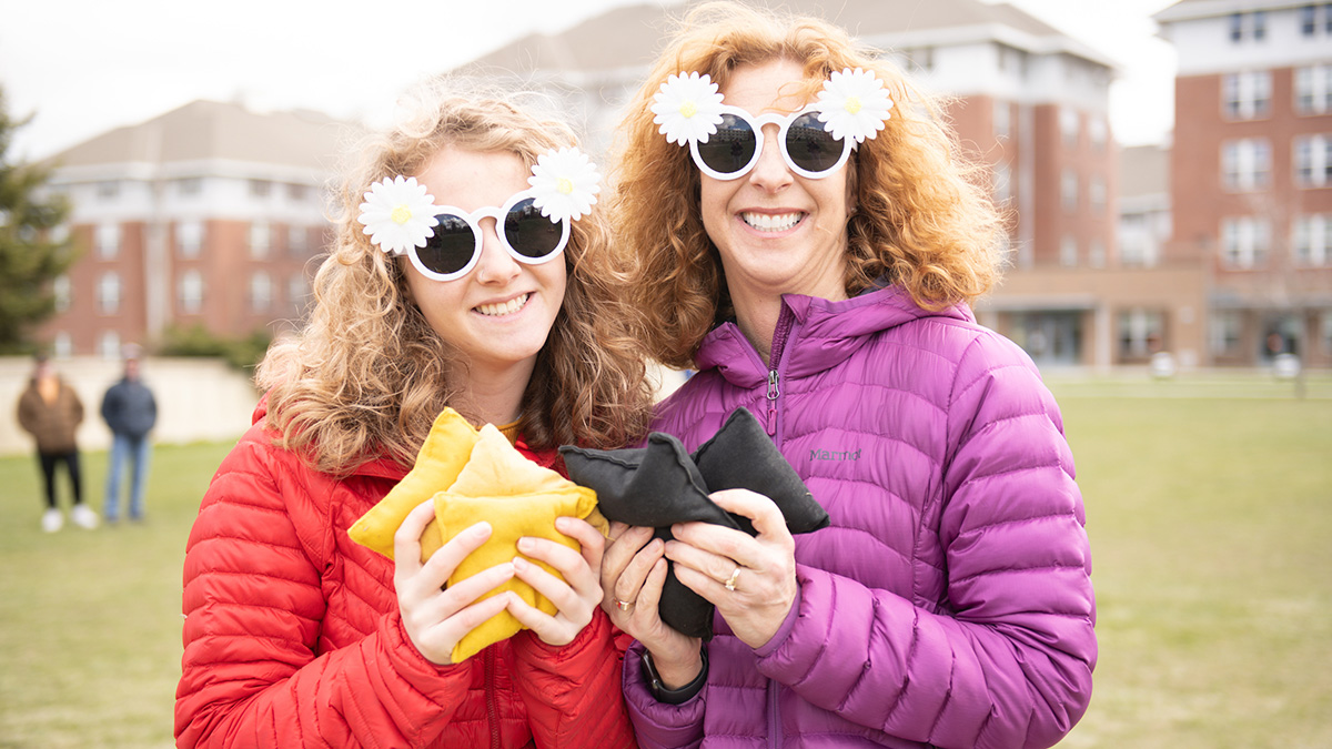Mother and daughter hold up bean bags for a game of cornhole.