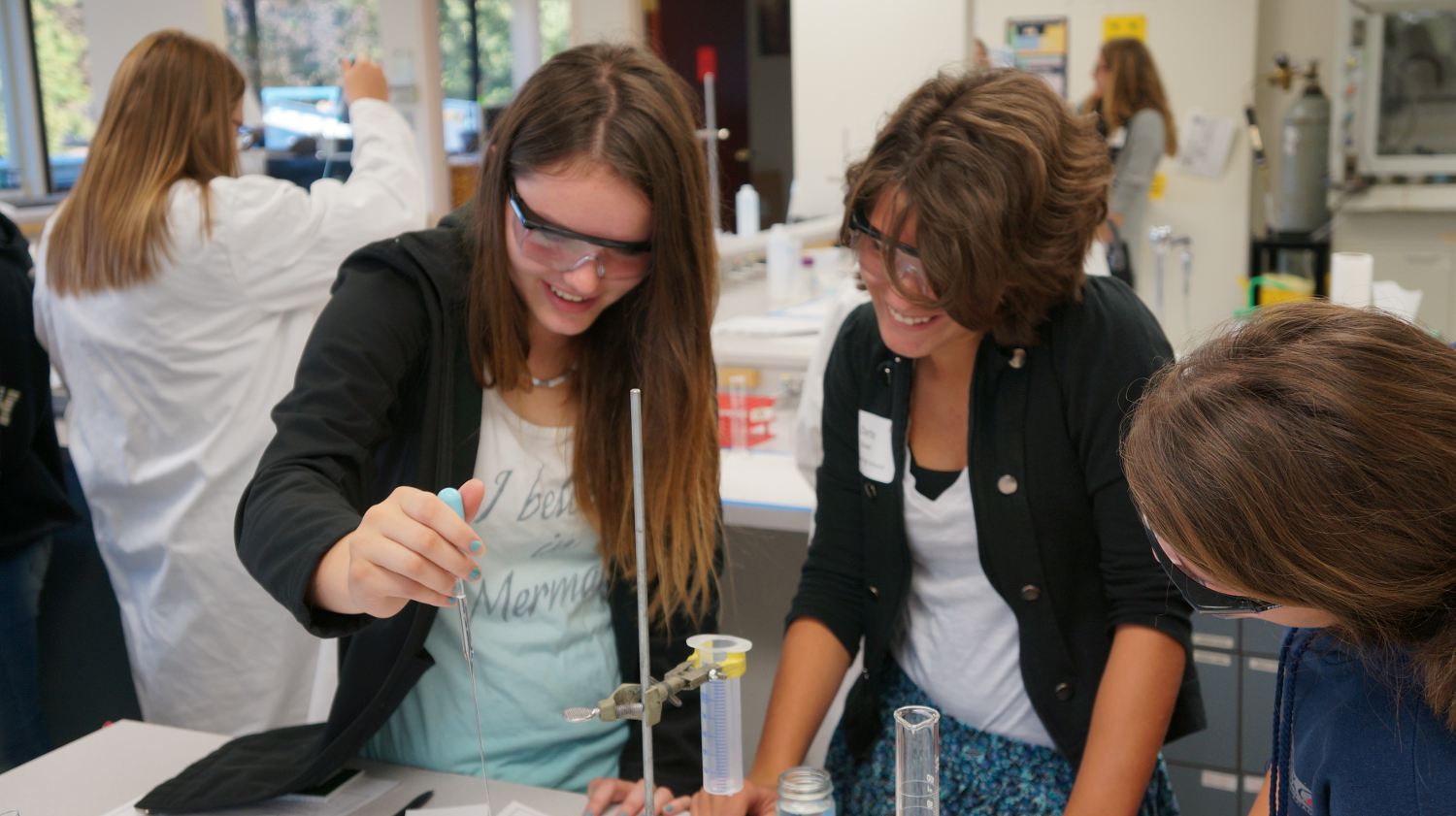 Young women running science experiments in a lab setting.