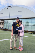 A mother and son stand on the practice field of the ASUI-Kibbie Activity Center.