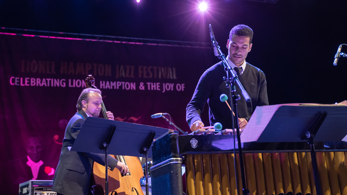 A performer plays xylophone while another plays bass.
