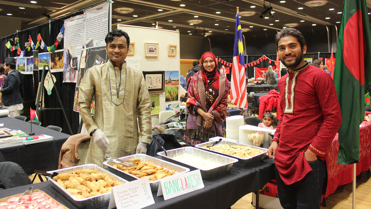 Students pose around a buffet of international cuisine.