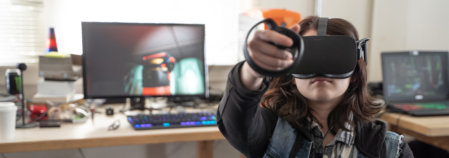 A student wears a virtual reality headset and interacts with the virtual world.