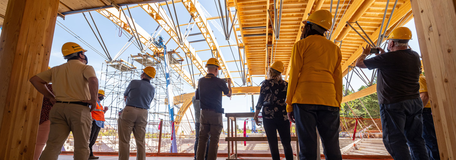 Visitors in hard hats watch the construction of the ICCU Arena.
