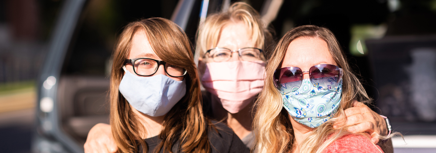 A mother and her children hug while wearing masks