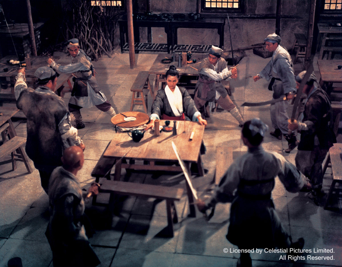 A screenshot form the film "Come Drink With Me," with a lady at table surrounded by seven swordsmen.