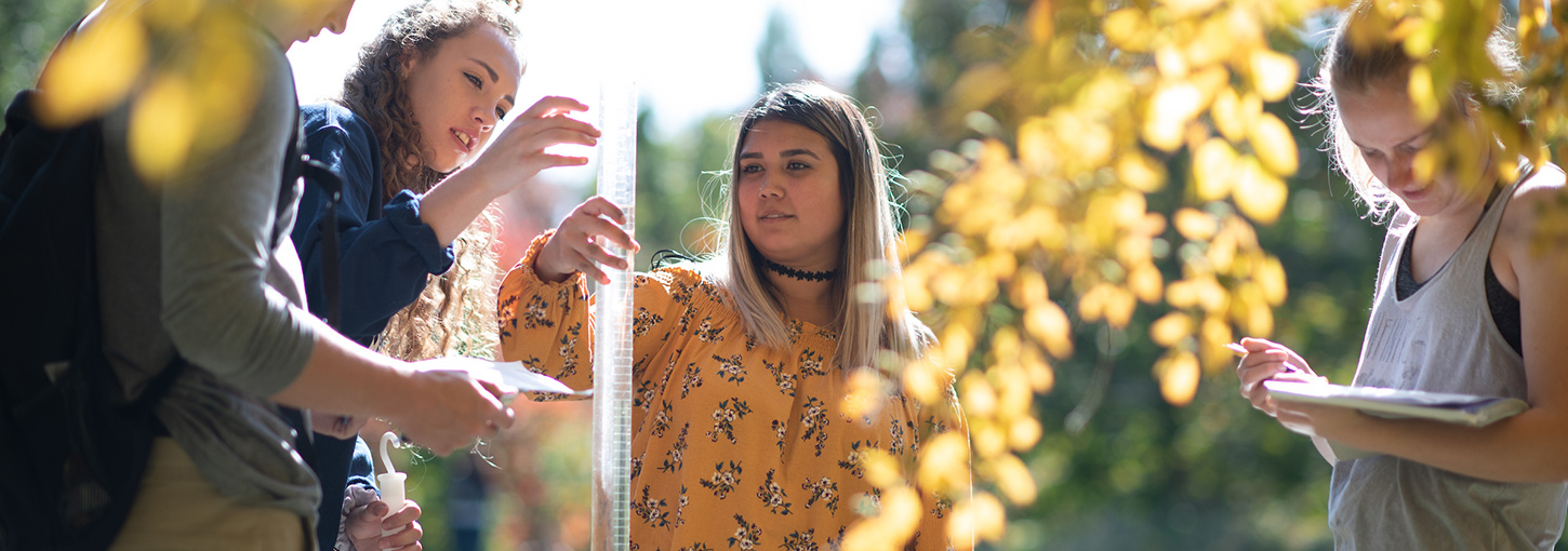 A student holds a graduated cylinder of pond water