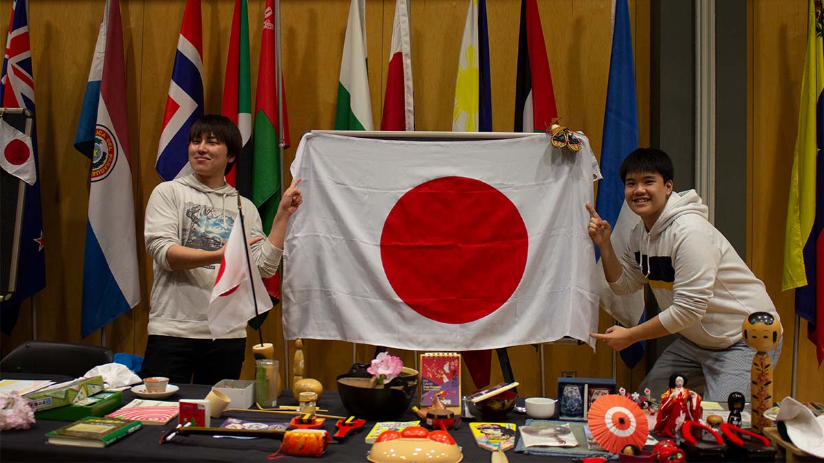 Two students in front of the Japanese flag.