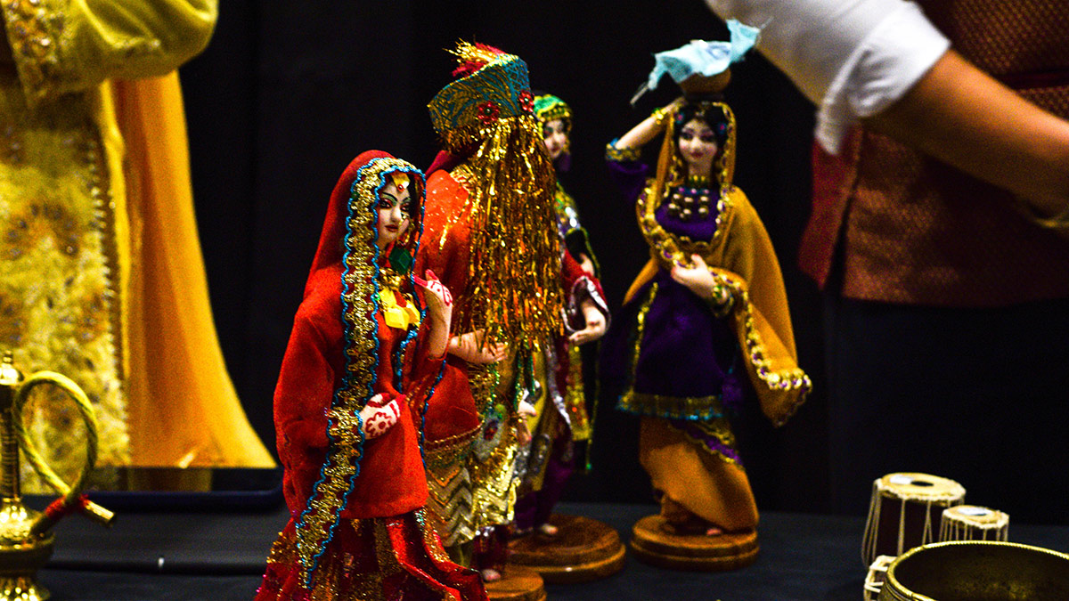 Four mall figurines dressed in traditional Pakistani wedding or celebratory clothing.