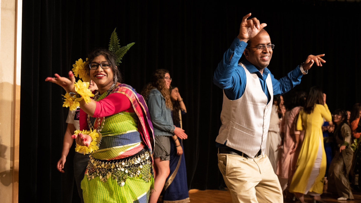 A couple dancing on stage during an open dance in traditional Bengali attire