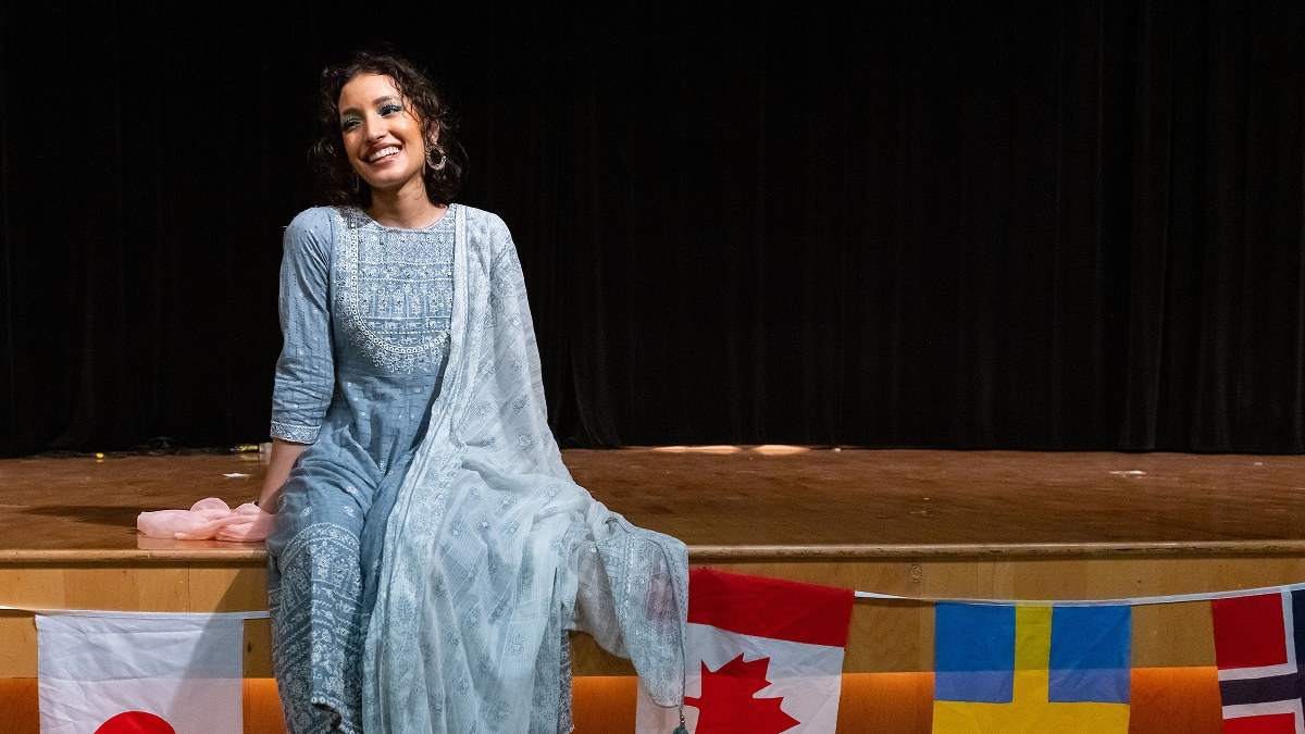 International student dressed in traditional garb while sitting on stage