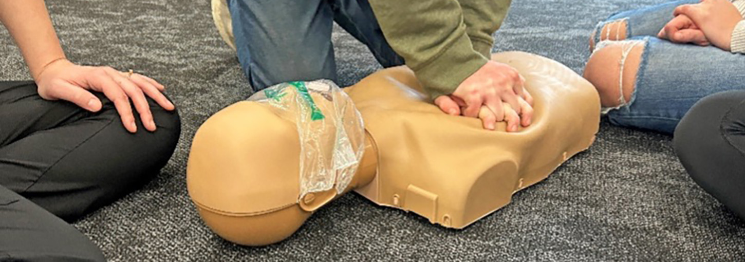Students performing compressions on cpr model.