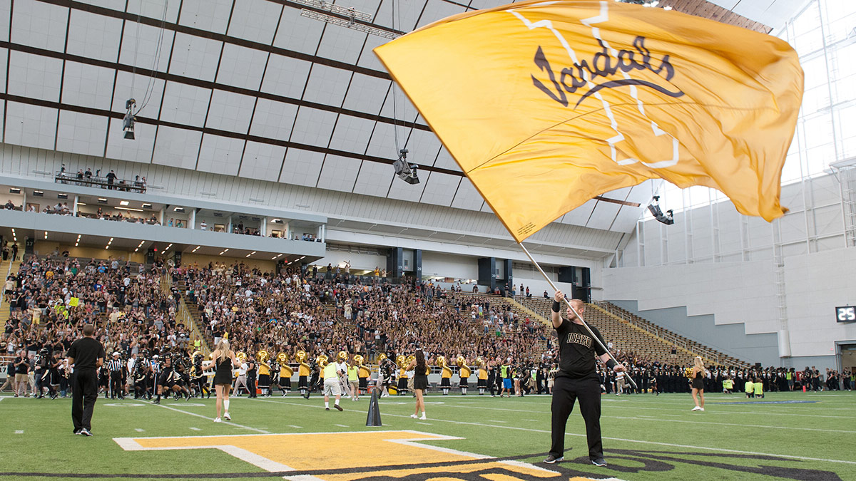 Someone waves a giant gold Idaho Vandals flag on the football field in the P1FCU KIbbie Dome.