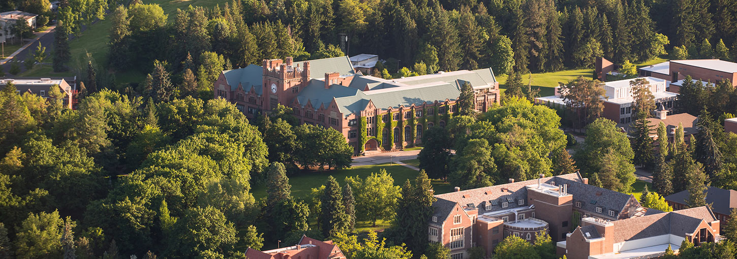 An aerial view of the U of I Moscow campus, showcasing green trees and the Administration Building.