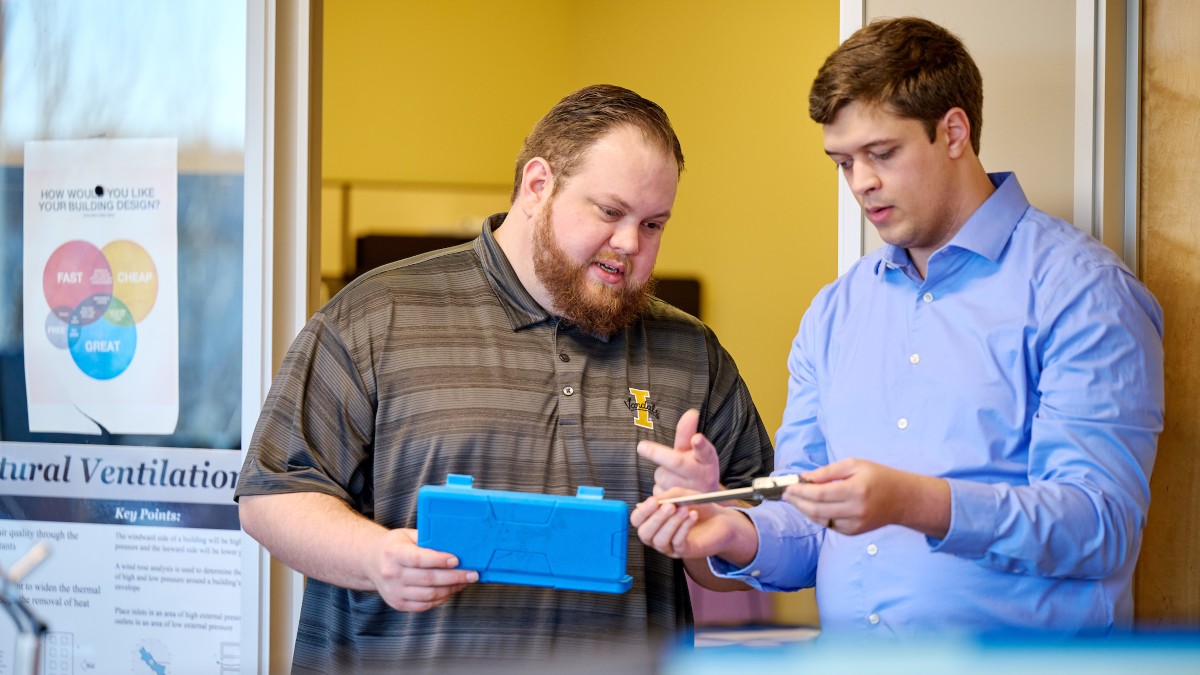 Two staff members discuss a tool in the integrated design lab. 