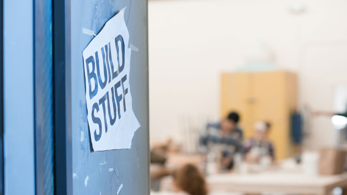 A blue wall with a sign reading "Build Stuff." A design studio is visible in the background.