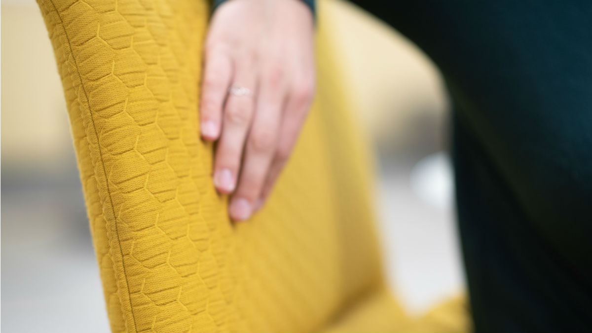 A student's hand feels the upholstery on a new pride gold chair.