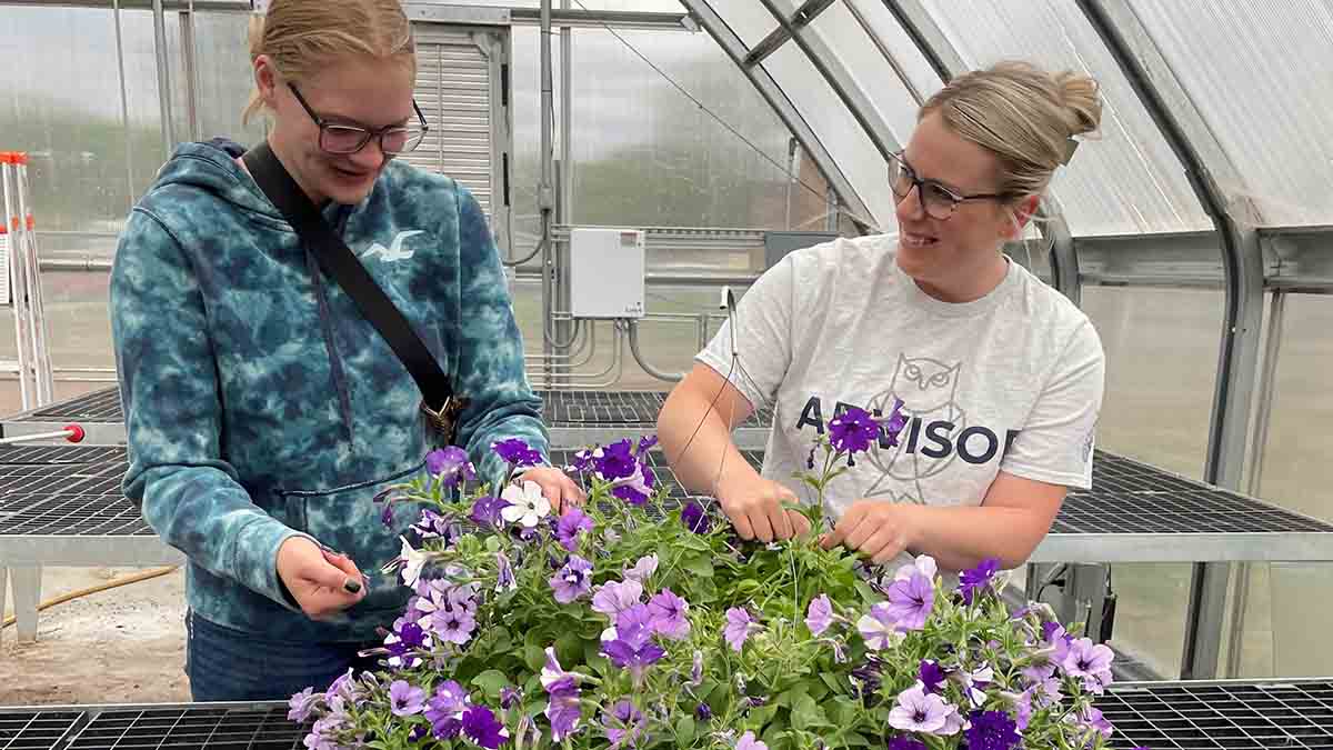 Two women in a greenhouse.